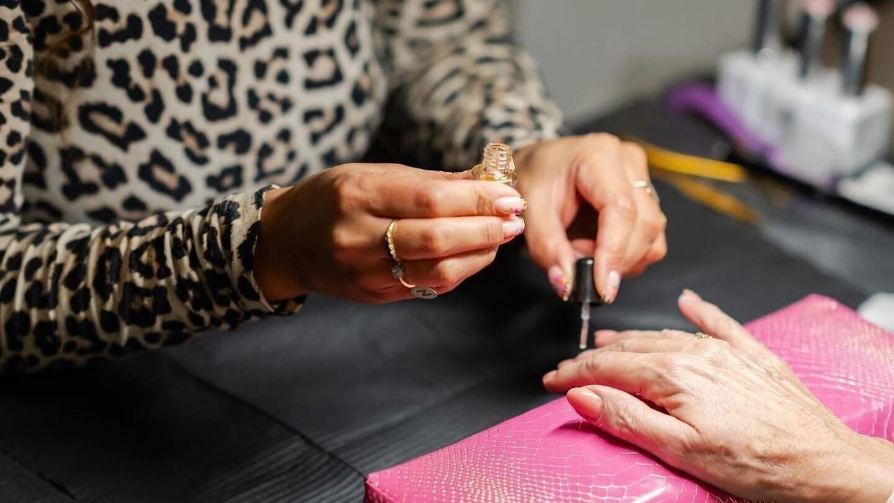 Nagels worden gelakt aan de tafel, op een roze onderlegger
